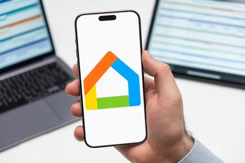 Google Home logo on the screen of mobile phone in mans hand Stock Photos