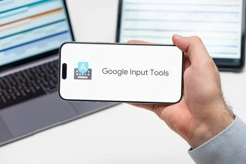 Google Input Tools logo of app on the screen of mobile phone held by man Stock Photos