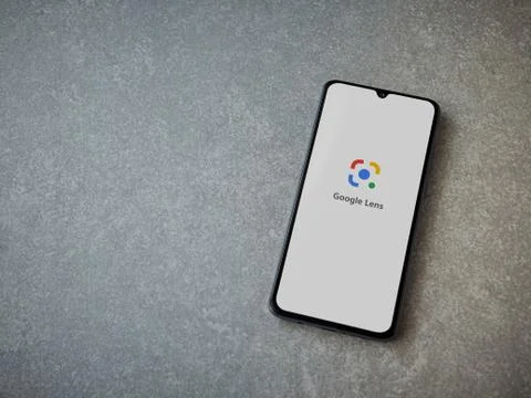 Google Lens app launch screen with logo on the display of a black mobile smar Stock Photos