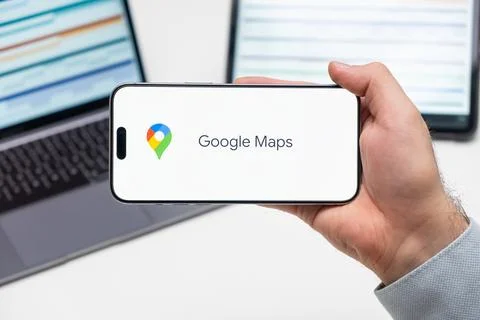 Google Maps logo of app on the screen of mobile phone held by man in front of Stock Photos