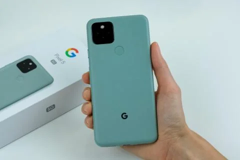 Google Pixel 5 in Sorta Sage color next to its box. Stock Photos