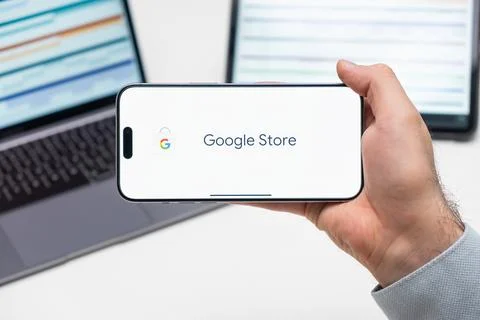 Google store logo of app on the screen of mobile phone held by man in front of Stock Photos