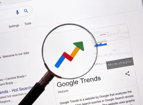 Google Trends web site and logo under magnifying glass Фото
