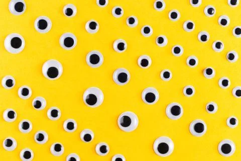 Googly plastic eyes pattern on yellow backgroud. Flat lay Stock Photos