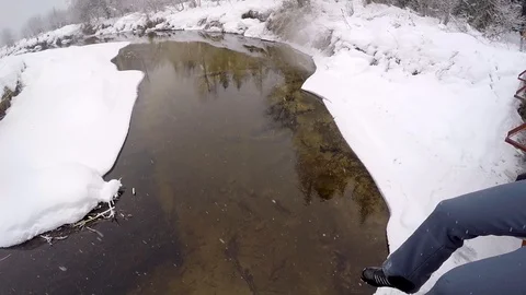 GoPro Pan of legs dangling over creek in winter Video stock 86448725