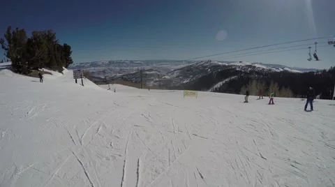 GoPro Skiers going down a slope and chairlift going up sunny day Park City Utah Stock Footage 61863560