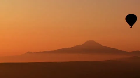 Gorgeous aerial shot of a hot air balloon silhouetted against distant mountains Stock Footage