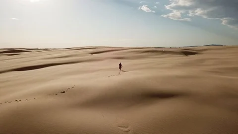 Gorgeous Aerial view of a lonely woman walking in the desert - 4K Stock Footage