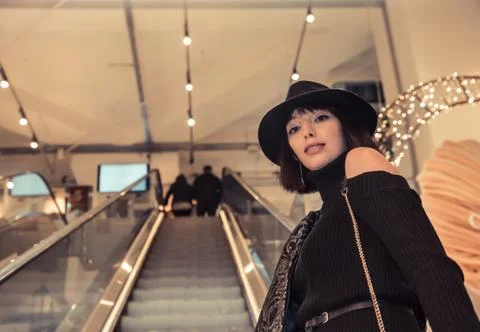 Gorgeous beautiful model with hat posing on escalator Stock Photos