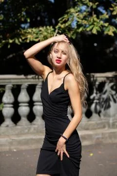 Gorgeous blonde model with long hair and red lips wearing black dress, posing Stock Photos