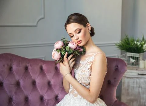 Gorgeous bride posing in white wedding dress, makeup, jewelry, bouquet Foto stock