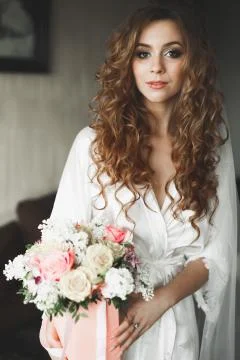 Gorgeous bride in robe posing and preparing for the wedding ceremony face in a Stock Photos