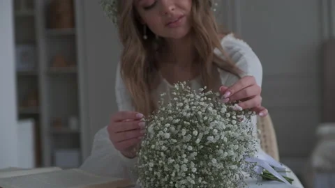 Gorgeous bride sits at the table and touches the bouquet Vidéo 182818510
