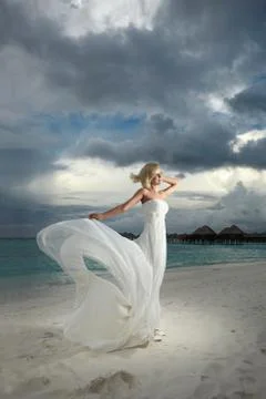 Gorgeous bride standing and posing under threatening clouds at sunset. Stock-Fotos