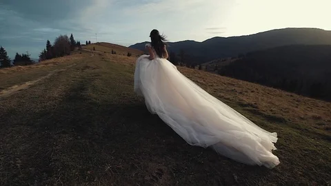 Gorgeous cheerful bride is running along the fantastic meadow. Beautiful nature Stock Footage