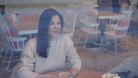 Gorgeous dark-haired, charmingly smiling woman sits in a cafe and looks out of Stock Footage 148268696