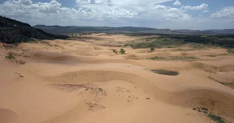 Gorgeous flight over rolling sand dunes near mountains under sunny sky Video stock 119121875
