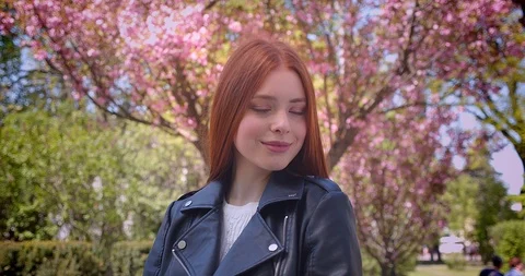 Gorgeous ginger model in leather jacket posing prettily into camera in pink Video stock 107976821