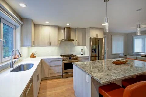 Gorgeous kitchen design features ivory kitchen cabinets flanking modern steel Stock Photos