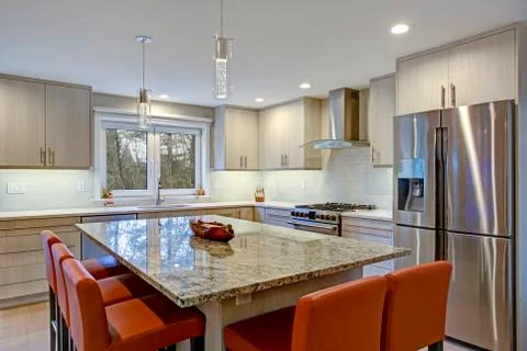 Gorgeous kitchen design features ivory kitchen cabinets flanking modern steel Stock Photos