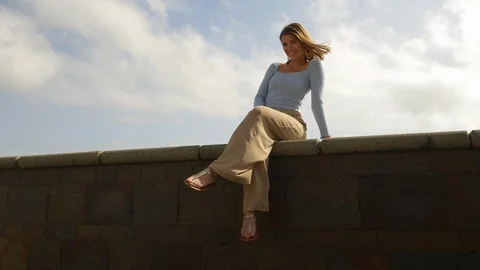 Gorgeous Model Sitting and Posing by the Seawall 스톡 동영상 115843406
