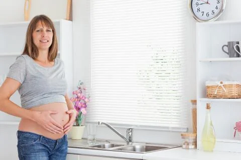 Gorgeous pregnant female posing while caressing her belly Stock Photos