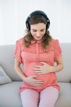 Gorgeous pregnant woman listening to music sitting in the living room Stock Photos