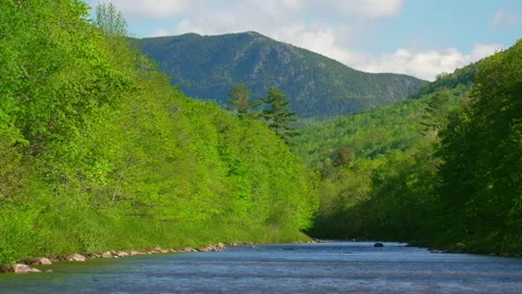 Gorgeous shot of broad river with spring green trees and granite peak. Stock Footage 144460351