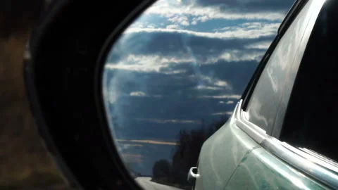 Gorgeous sky and back road reflected in car side mirror. Car driving slow motion Stock Footage 89615415