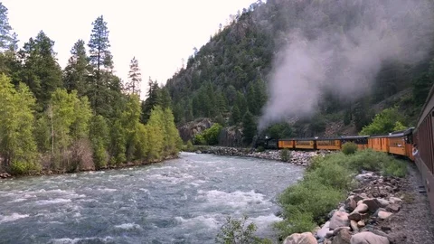 Gorgeous steam engine pulls train through mountain river valley Stock Footage 113876589