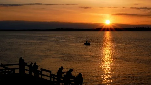 Gorgeous sunrise with sun rays over lake with silhouettes of people fishing. Stock Footage 108676506