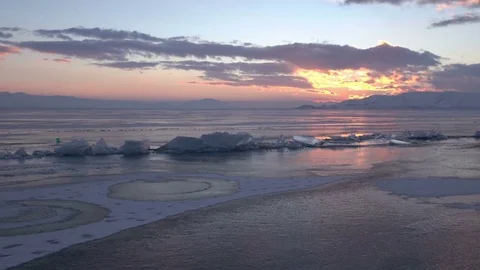 Gorgeous sunset over small icebergs and icicles in the frozen lake Stock Footage 73299128