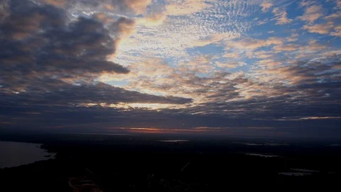 A gorgeous sunset peaking through the white clouds and blue sky in Florida Stock Footage 128850113