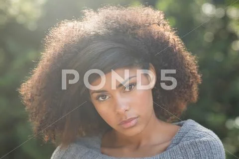 Gorgeous unsmiling brunette standing in sunshine looking at camera Stock Photos