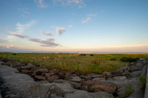 A Gorgeous View of Sand Dunes Covered in Plants With the Ocean and Sky Over T Stock Photos