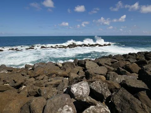 Gorgeous waves slapping against the rocks on a sunny day at a tropical island 库存照片
