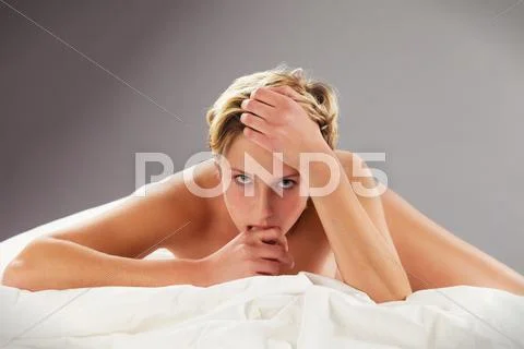 Gorgeous woman bites on her finger on bed Stock Photos