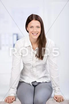 Gorgeous young female sitting on the desk Stock Photos
