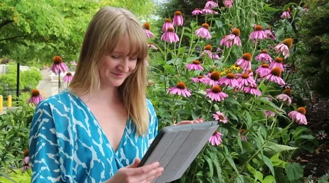 Gorgeous young female using tablet PC in garden Stock Footage 52801246