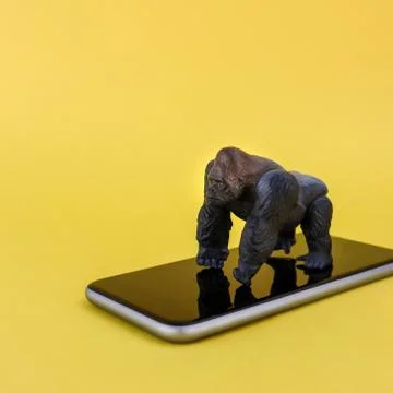 Gorilla toy on smartphone yellow background Stock Photos