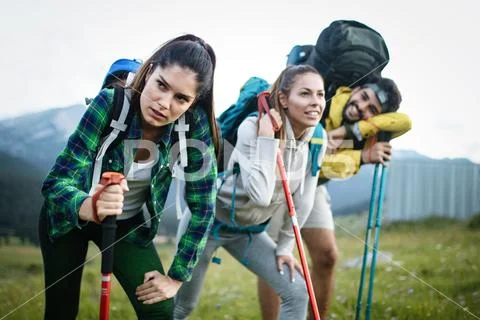 Gorup of friends climbing up hill, with backpacks and climbing stick Stock Photos