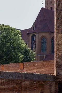 Gothic brick castle architecture with statue and lush green trees under a c.. 스톡 사진