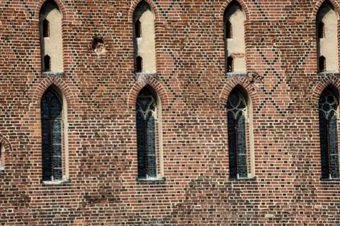 Gothic brick wall with pointed arched windows and decorative patterns Stock Photos