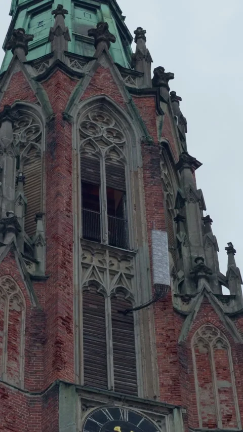 Gothic church tower with red brick facade, ornate tracery and green copper spire Stock Footage 346558942