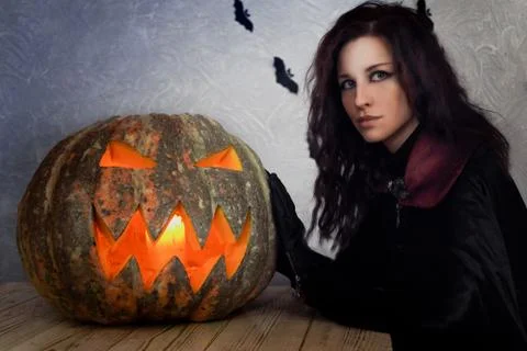 Gothic girl with pumpkin on the table Stock Photos