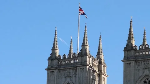 Gothic Revival Tower with Union Jack Flag Against Blue Sky 4K Stock Footage 332134126