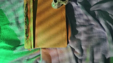 Gothic ritual scene with mystical props. Old book and skull with green streaks e Stock Footage 334551340