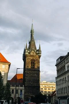 Gothic stone tower under cloudy sky. Sunset light hits medieval architecture. Stock-Fotos
