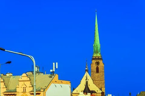 Gothic temple tower with a clock under an ultramarine sky behind street light Stock Photos