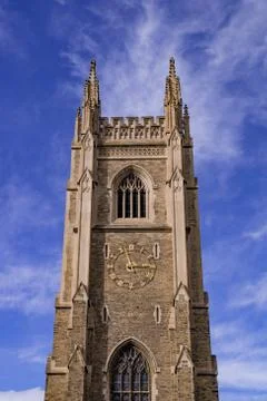 Gothic tower in front of bright blue sky with white cirrus clouds Stock Photos